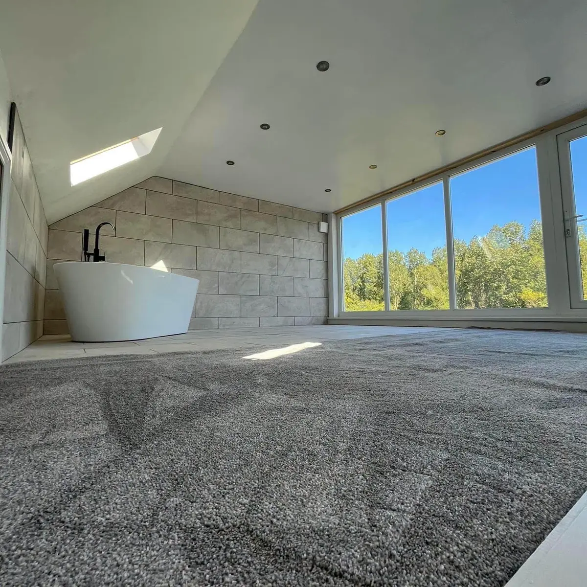 Freestanding bath under a vaulted window in a converted loft bathroom, Hebburn